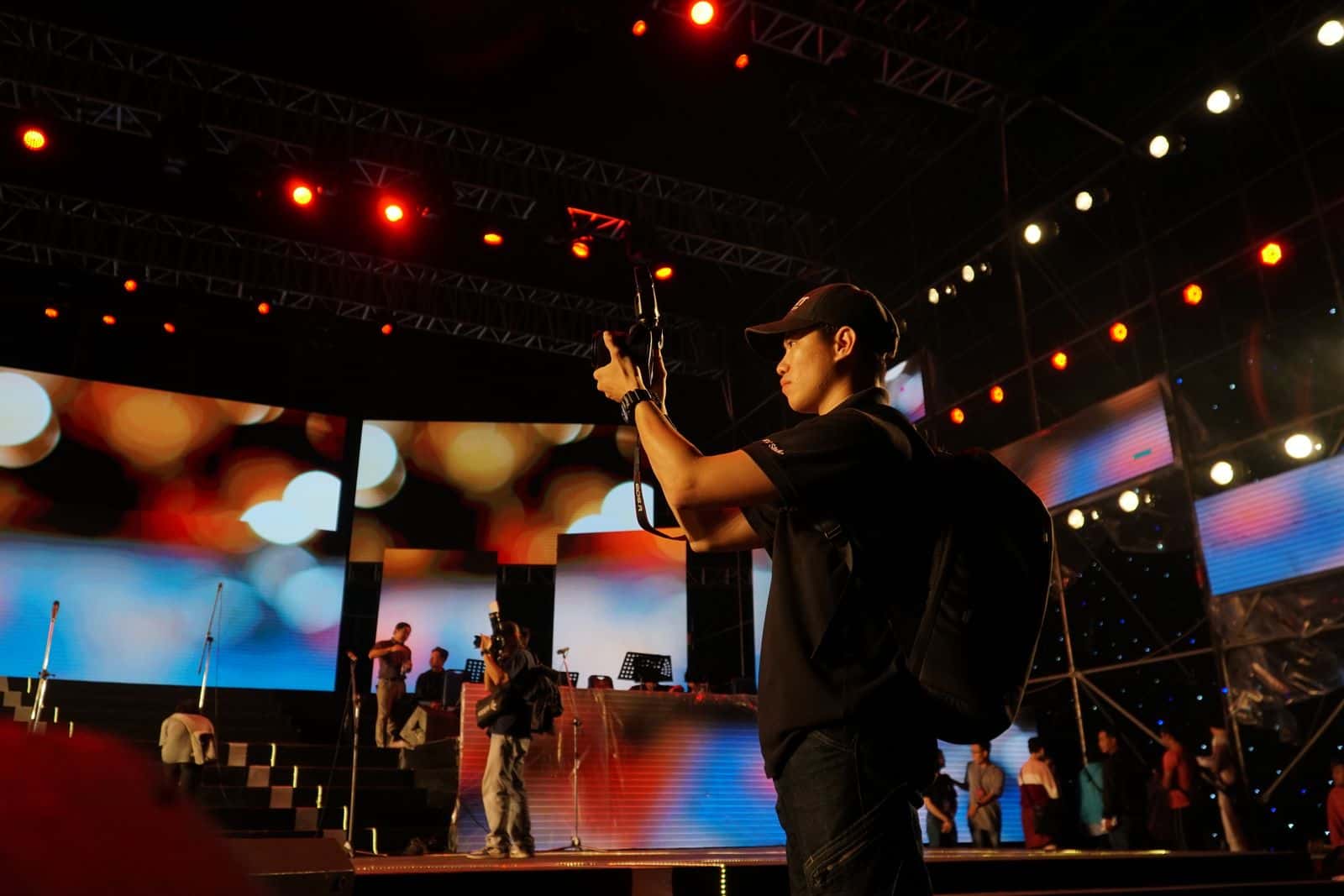 Event photographer working beside a lit conference stage