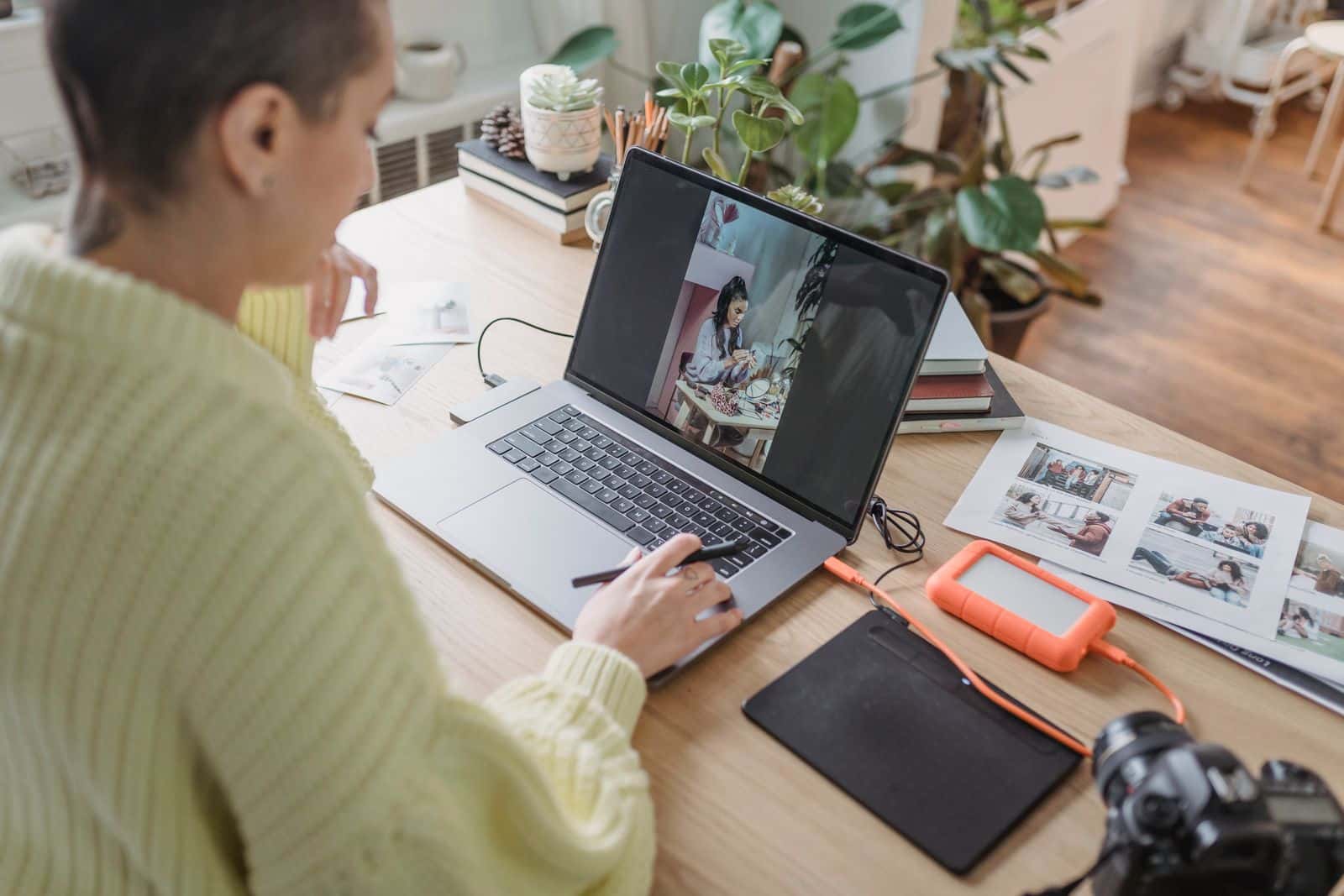 Fotografin bearbeitet Fotos am Laptop im Homeoffice mit Pflanzen