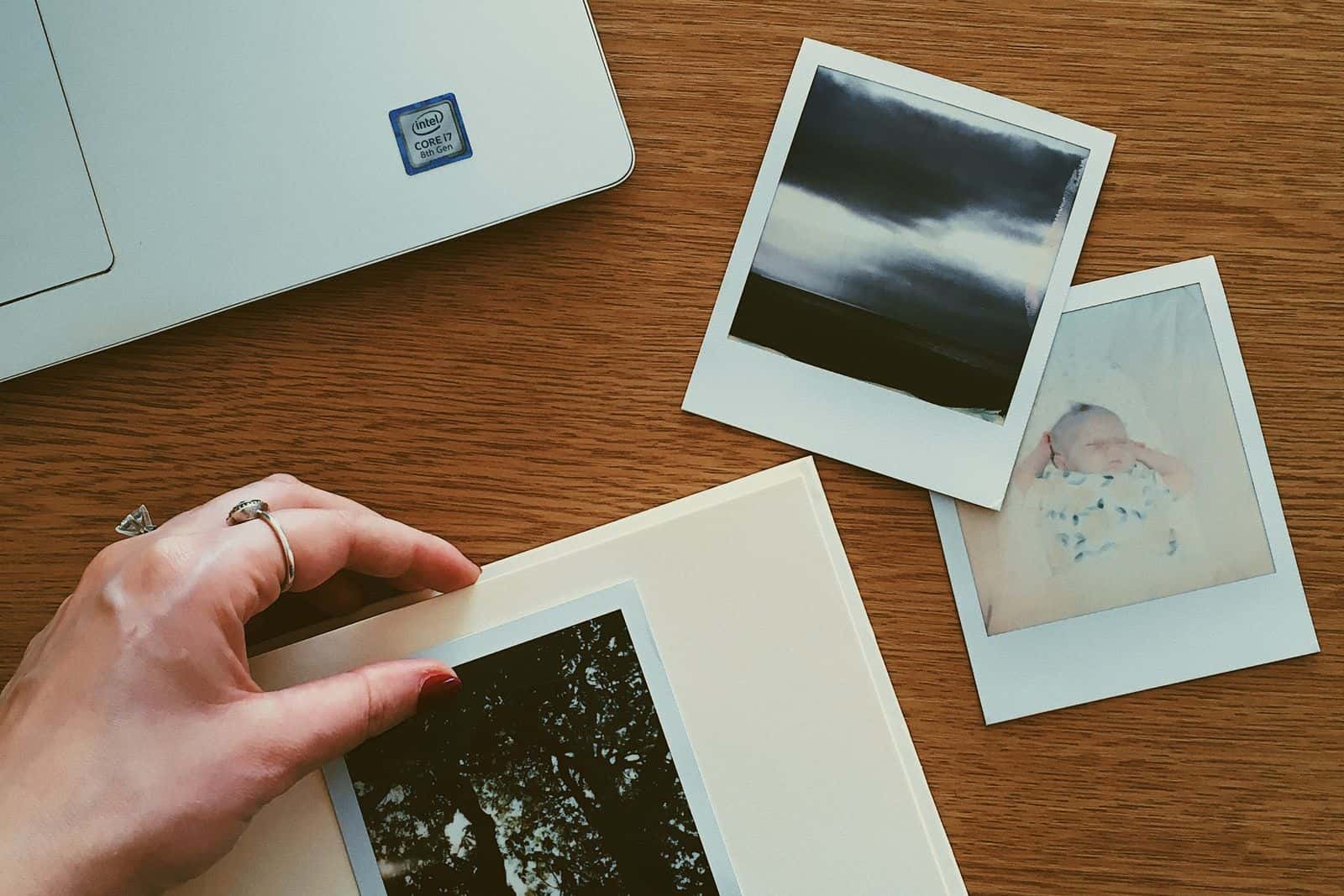 Hands arranging printed photographs into an album
