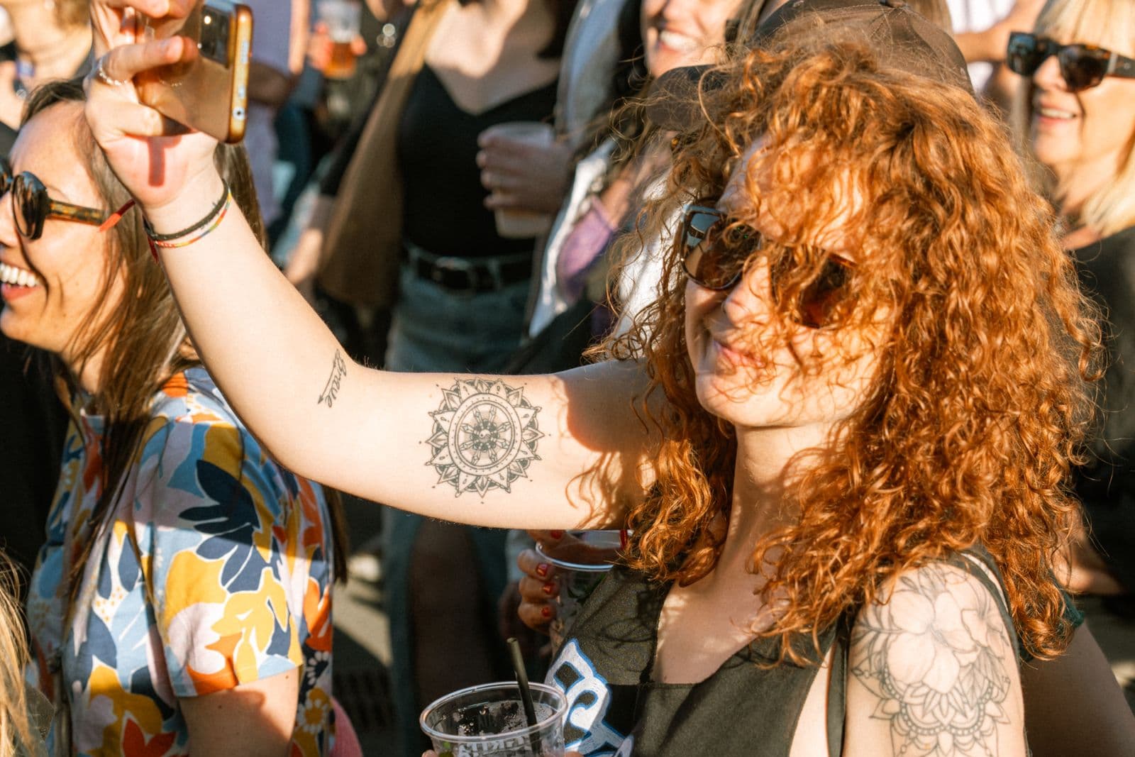Woman holding up a phone in an outdoor concert crowd