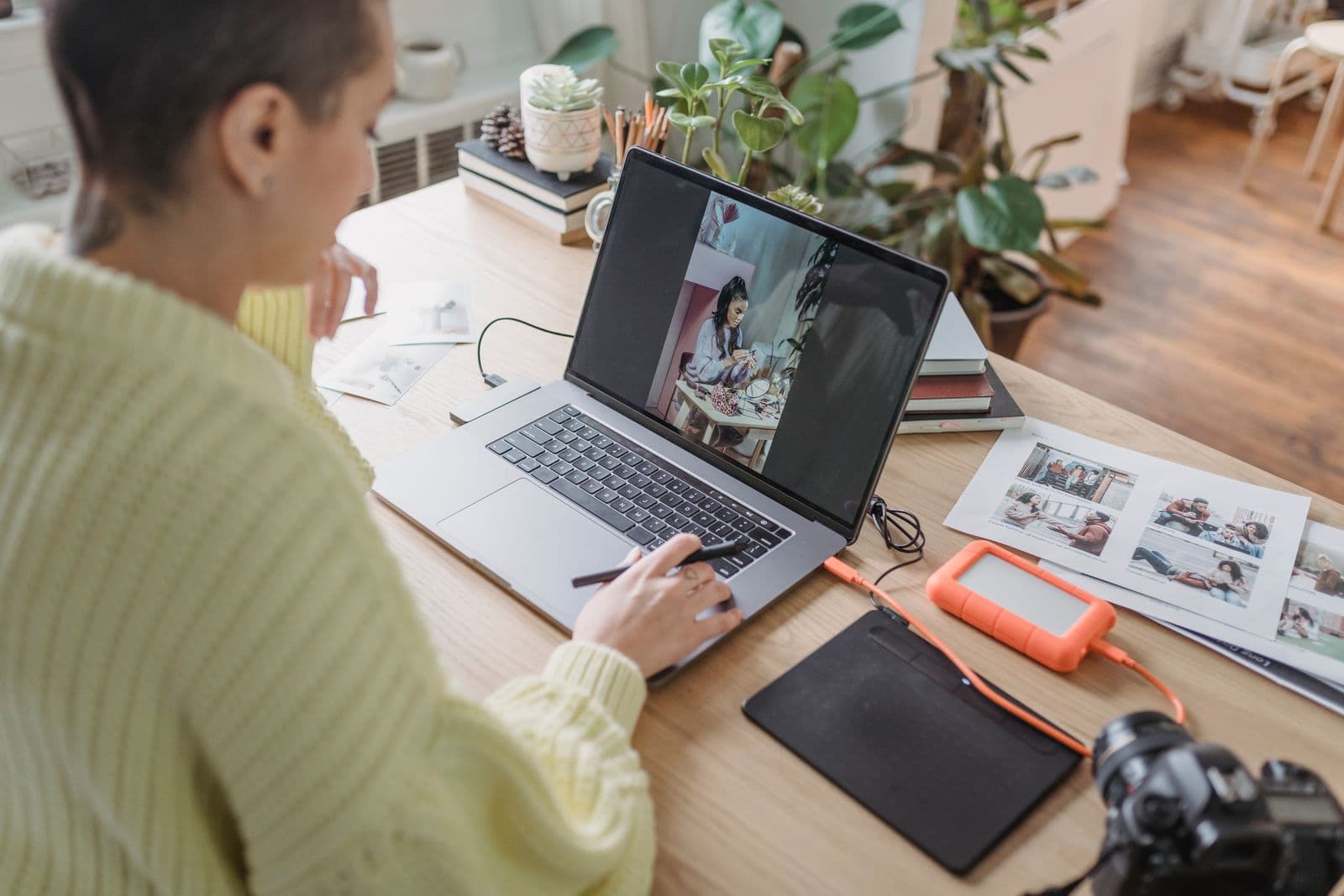 Fotografin bearbeitet Fotos am Laptop im Homeoffice mit Pflanzen