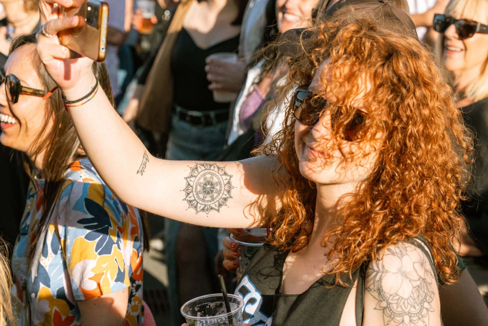 Woman holding up a phone in an outdoor concert crowd