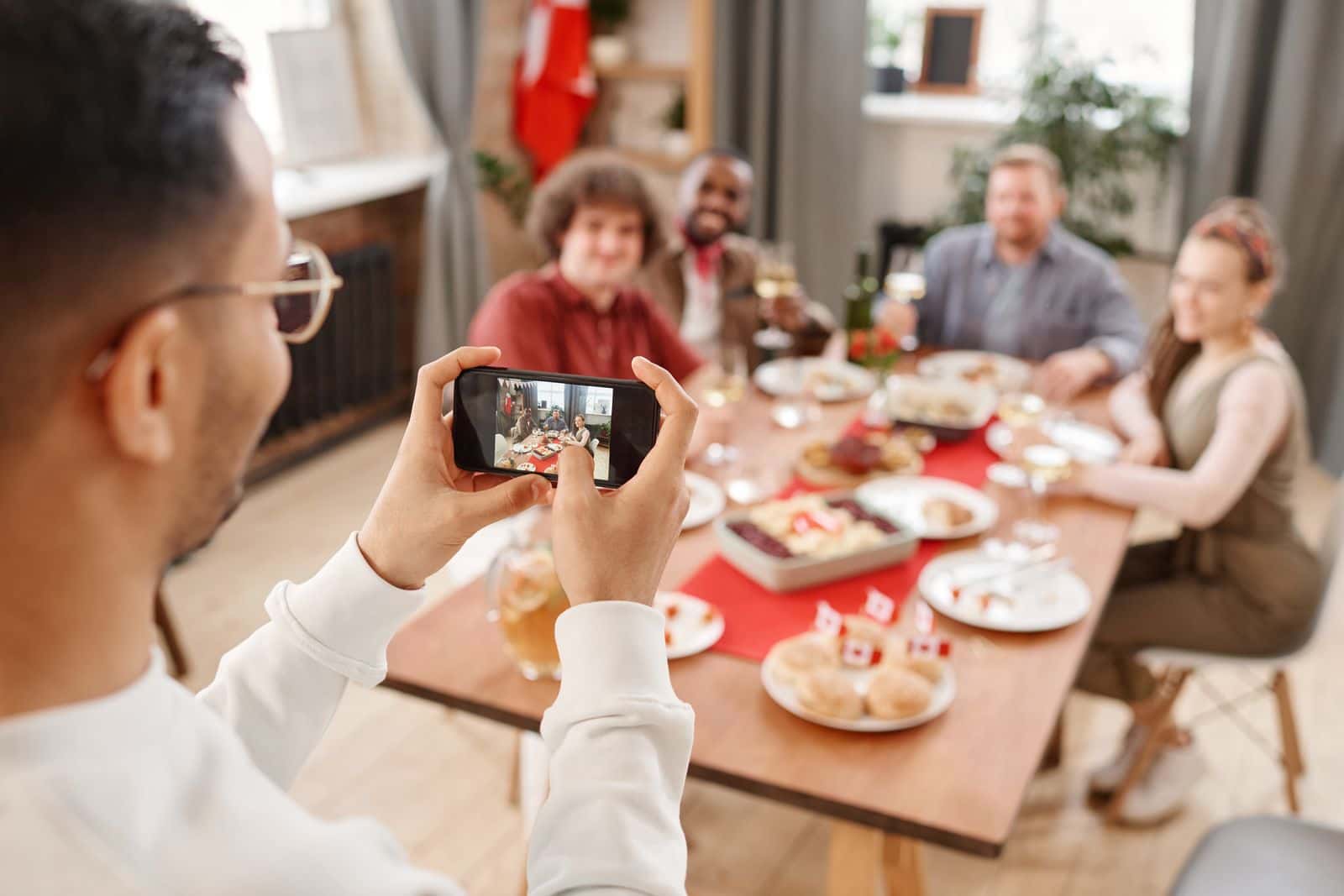 Guest using a phone to photograph friends around a dinner table