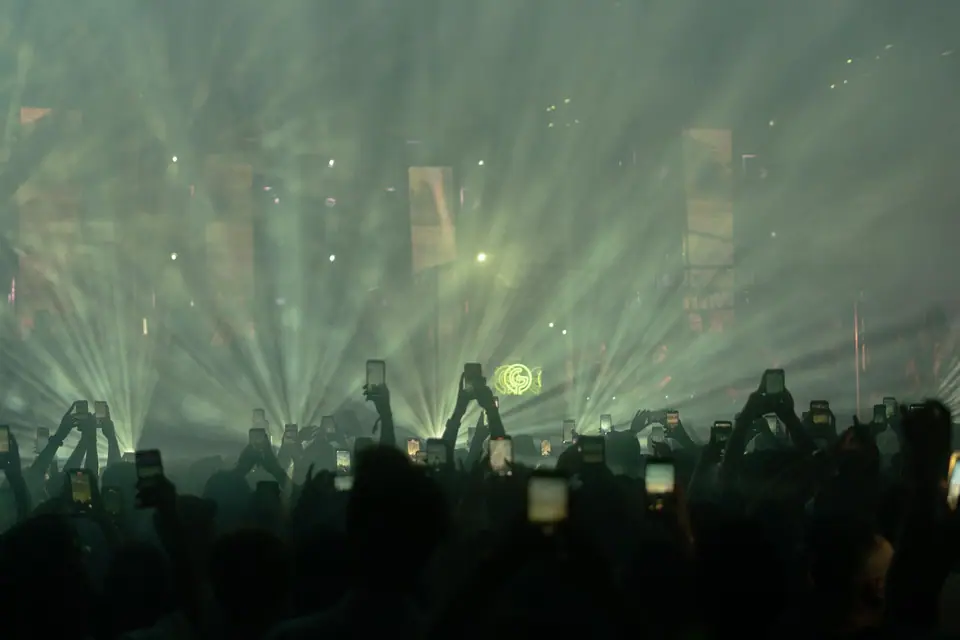 Concert crowd raising phones under stage lights