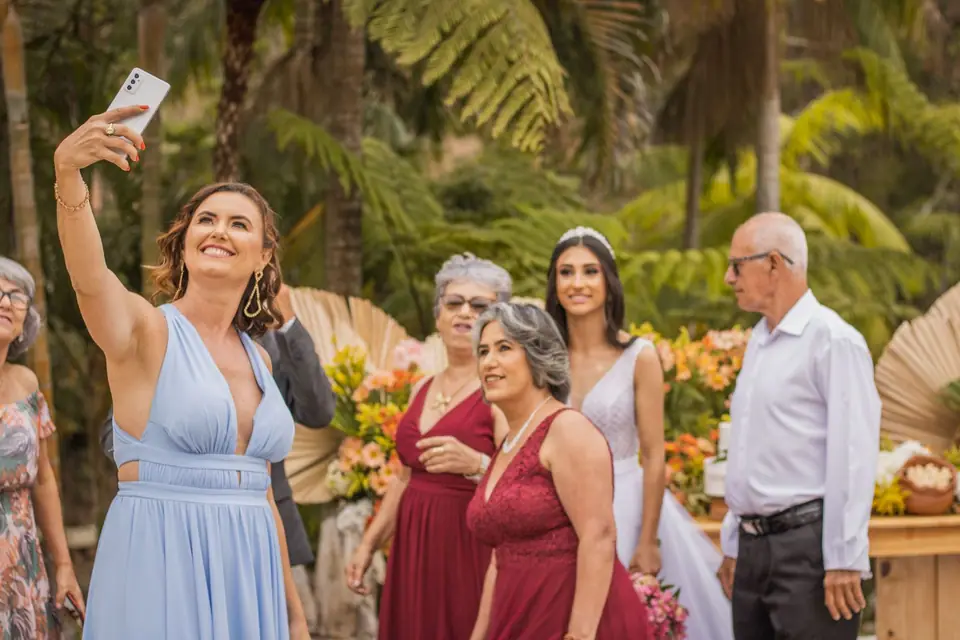 Wedding guests and the bride taking a group selfie at an outdoor reception