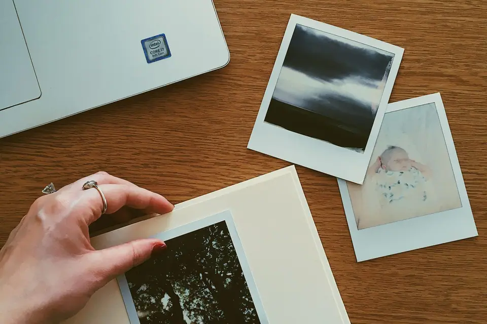 Hands arranging printed photographs into an album